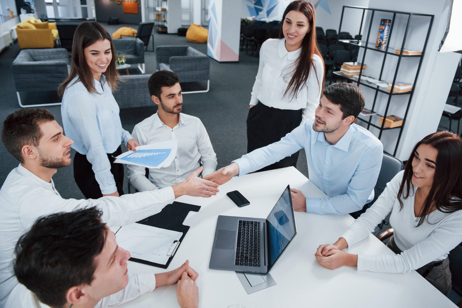 handshake-success-deal-top-view-office-workers-classic-wear-sitting-near-table-using-laptop-documents